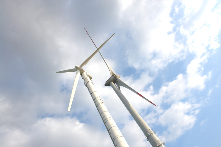 Das Foto zeigt zwei dicht nebeneinander stehende Windenergieanlagen, eine kleine und eine große.