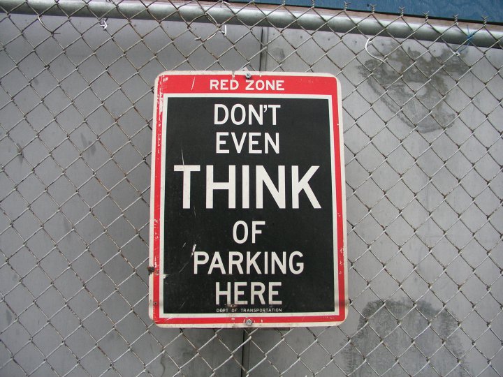 Das Schild auf dem Foto zeigt ein Parkverbot, red zone, don´t even think of parking here.