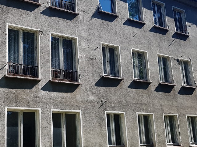 Das Foto zeigt die Fassade eines Gebäudes, mit grauem Putz und offenkundig sanierungsbedürftig.