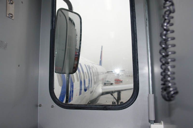 Zu sehen ist auf dem Foto ein Flugzeug, fotografiert durch das Fenster eine Gangway.