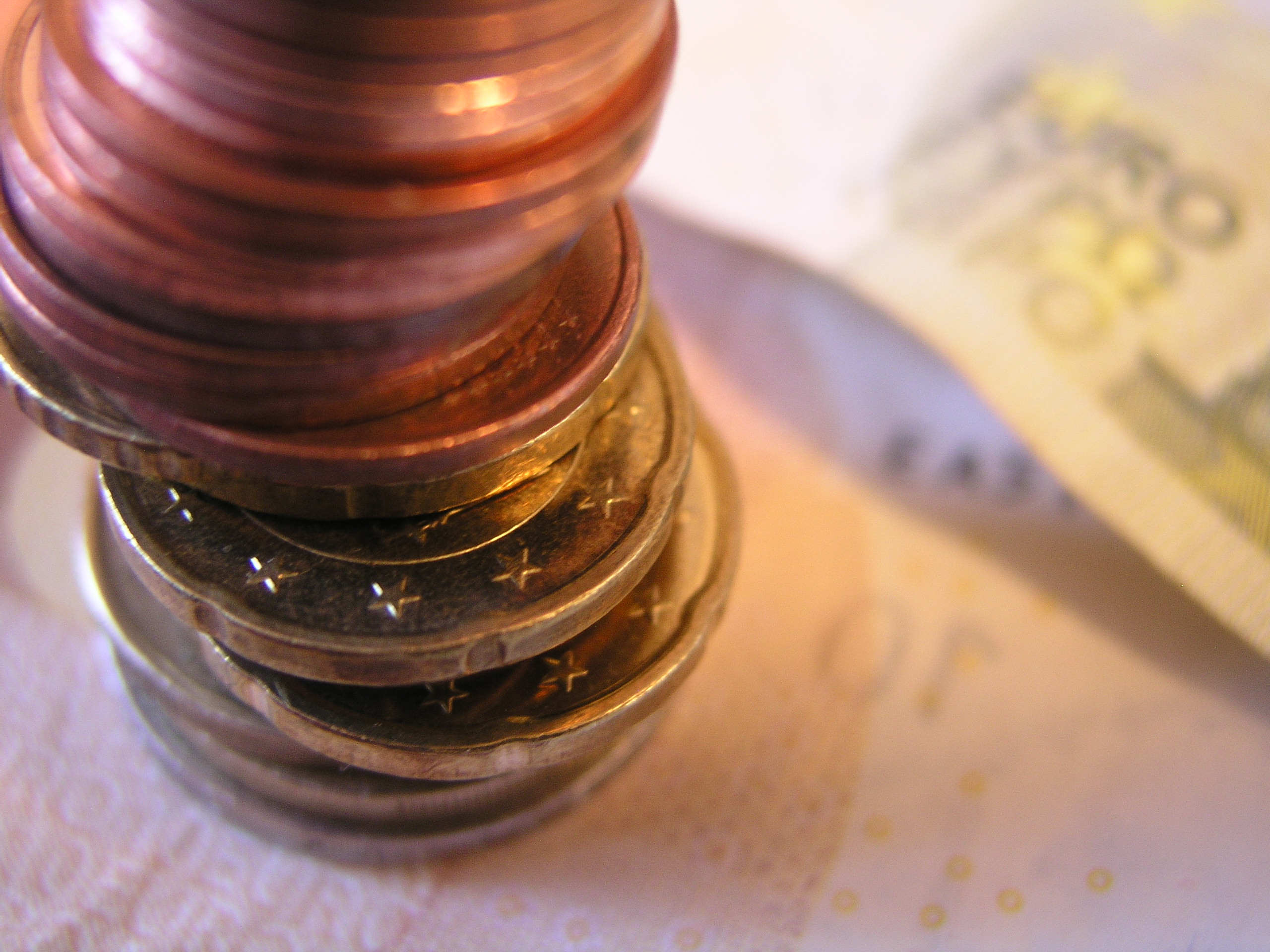 Das Foto zeigt Einen aus Münzen gebildeten Turm, der auf Geldscheinen steht.