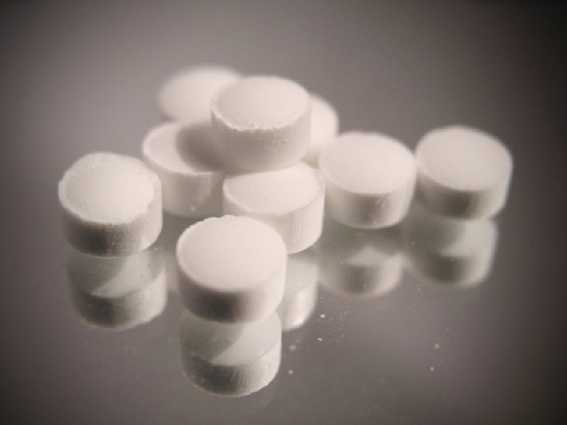 Das Foto zeigt einen kleinen Haufen Tabletten, liegend auf einer spiegelnden Oberfläche.