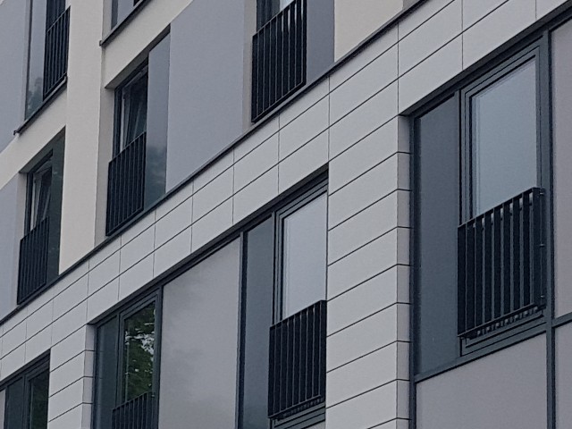 Das Foto zeigt den Ausschnitt einer Gebäudefassade mit einigen Fenstern und französischen Balkon in moderner Aufmachung.